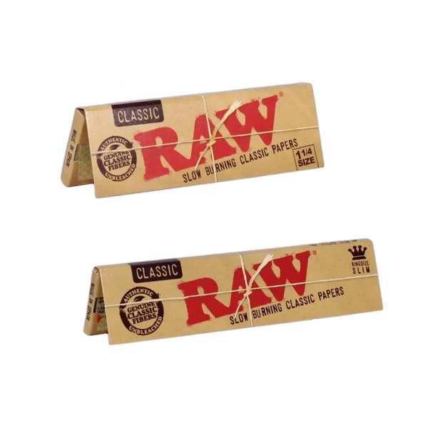 Two packs of RAW filters Classic Rolling Papers, one in 1¼ size and the other in King Size. Both packs feature RAW's iconic brown packaging with red bold letters and "Classic" written in the corner. The packaging emphasizes that the papers are slow-burning, made from unbleached, chlorine-free fibers, and include RAW's signature criss-cross watermark for even burning.