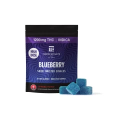 A package of Twisted Extracts High Dose Blueberry Sour Twisted Singles, featuring a dark purple gradient design with a swirl pattern, 1200mg THC, Indica, and blue gummy cubes placed in front of the package