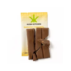 Kush Kitchen Banana Caramel chocolate bar broken into thick pieces showing 200mg THC on yellow packaging.