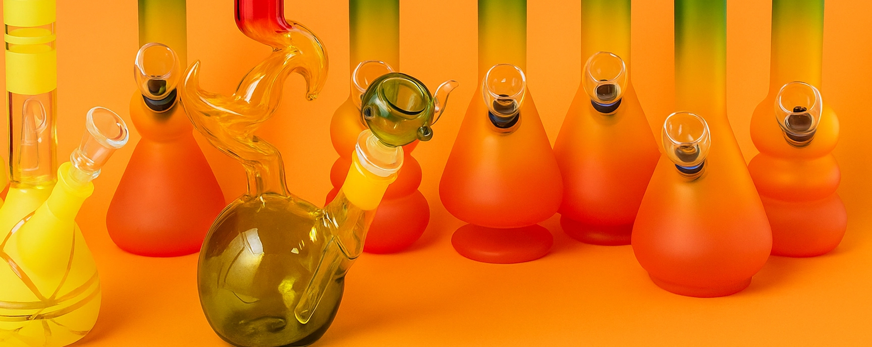 Colorful glass bongs displayed in a bong shop on a bright orange background.