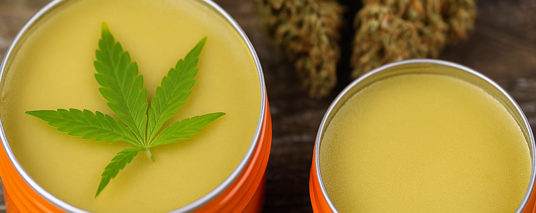 CBG cream in bright orange tins with cannabis buds on wooden surface