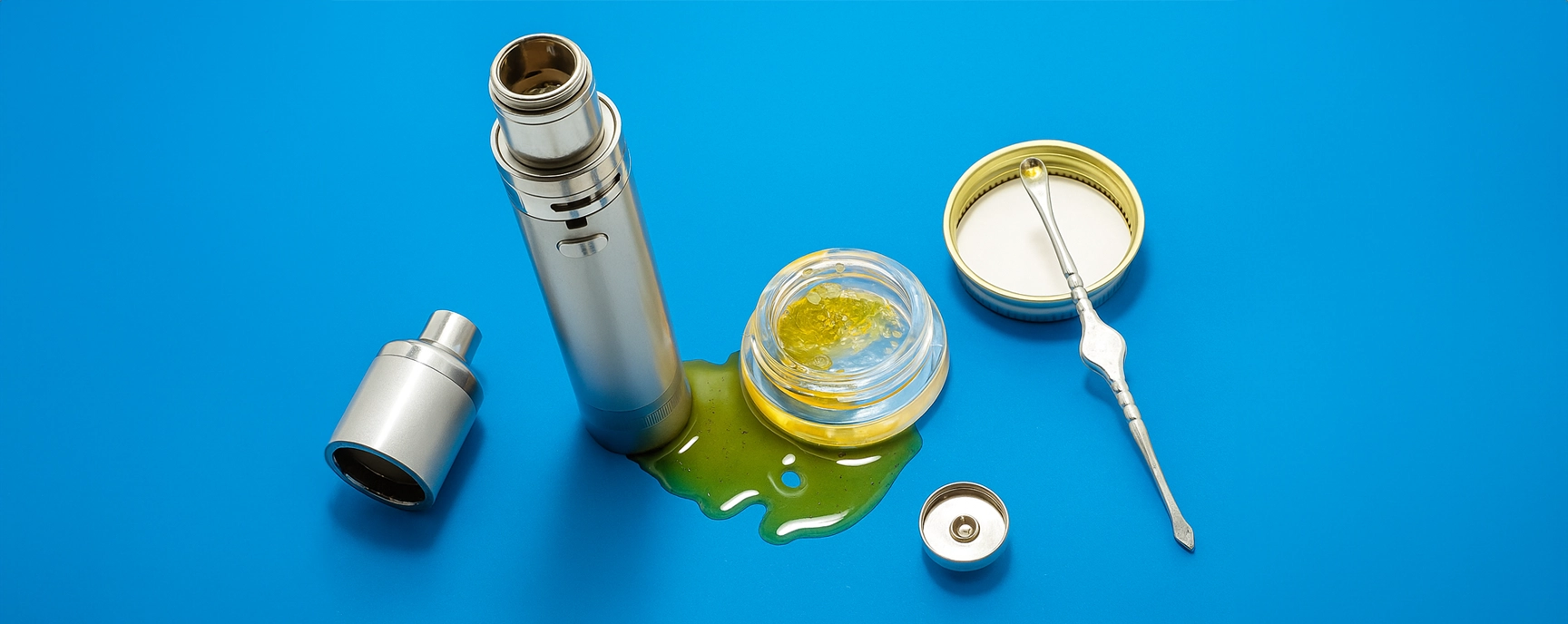 Dab pen and cannabis concentrate tools on blue background with spilled extract.