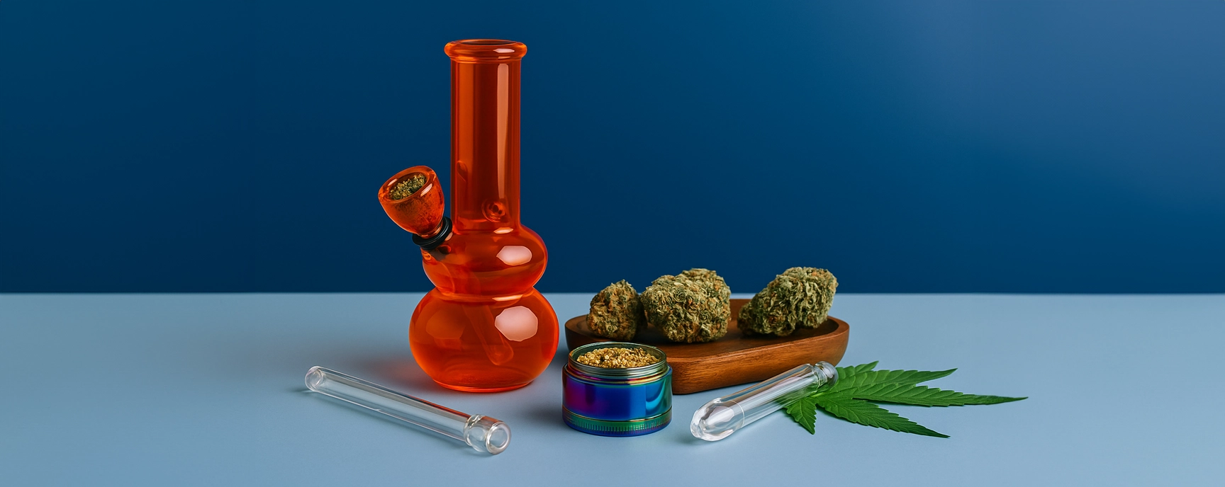 Bright and modern image of weed accessories including an orange bong, cannabis grinder, glass tubes, wooden tray with dried buds, and a cannabis leaf on a blue gradient background.