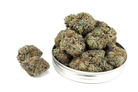 Tom ford pink kush strain buds displayed in a metal jar lid with two nuggets beside it, highlighting trichome-covered texture on a white background.